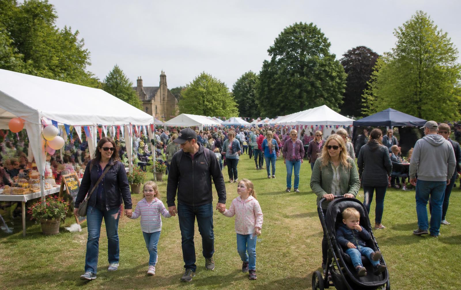 Families walking between marquees and stalls at a British community fun day